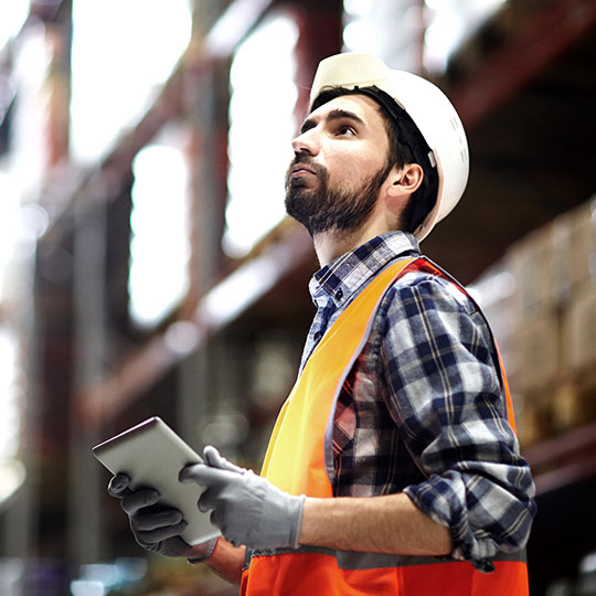 man wearing hard hat looking at tablet